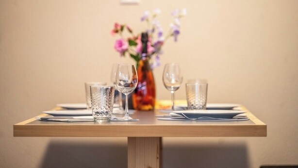 Ein Esstisch mit vier Gläsern und einer Blumenvase.