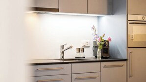 Eine moderne Küche mit Einbauofen, einer Kaffeemaschine und einem Blumenstrauß auf der Arbeitsfläche.