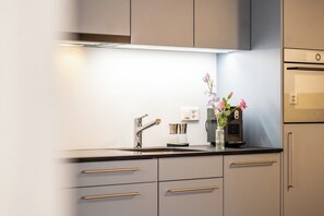 Eine moderne Küche mit Einbauofen, einer Kaffeemaschine und einem Blumenstrauß auf der Arbeitsfläche.