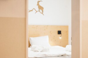 A hotel room with a wooden headboard, a bed with white linens, and a wall-mounted light fixture. - Where Mountain Mornings Feel Extraordinary 1094 (Wallis)