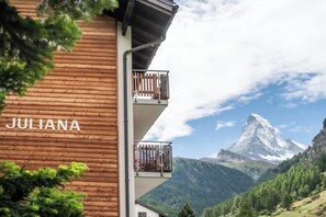 Ein Holzgebäude mit dem Namen 'JULIANA' und Balkonen mit Blick auf eine gebirgige Landschaft.