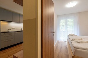 A modern bedroom with a wooden floor, a bed with white linens, and a view of the outdoors through a window. - Chic Alpine Retreat with Views 1095 (Wallis)