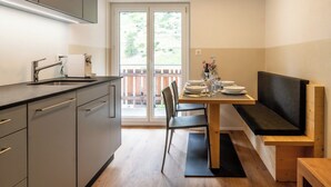 A compact kitchen with a sink, cabinets, and a dining area with a bench and table. - Chic Alpine Retreat with Views 1095 (Wallis)