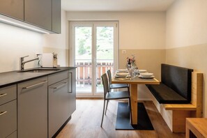 Eine kleine Küche mit Spüle, Schränken und einem Essbereich mit einer Bank und Tisch.