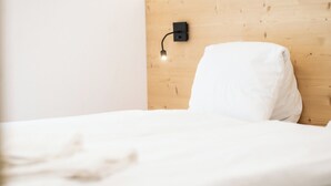 A bed with a white mattress and pillow against a wooden headboard. - Chic Alpine Retreat with Views 1095 (Wallis)