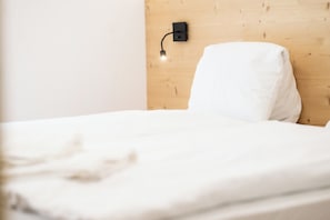 Ein Bett mit weißer Matratze und Kissen vor einem Holz-Kopfstück.