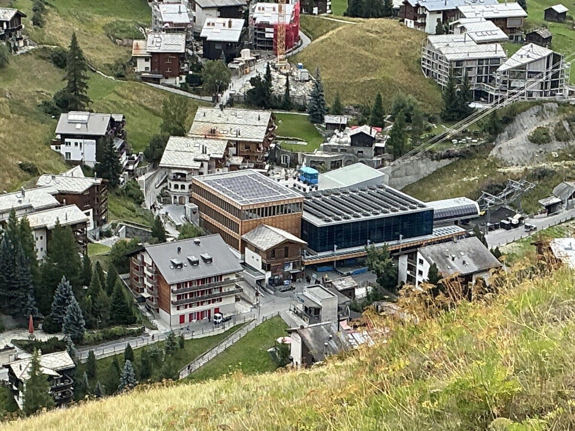 Une ville où se côtoient des immeubles résidentiels et commerciaux, notamment un grand bâtiment moderne doté d’un toit plat et un bâtiment traditionnel plus petit, avec un toit en pente.