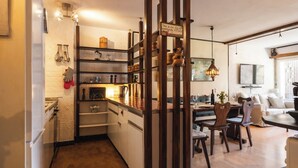 A kitchen with wooden shelving, a dining area with a table and chairs, and a living room with a sofa and a television. - Luxury  in Perfect Location, Valais  1410 (Valais)