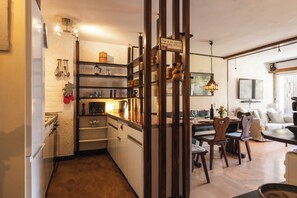 Eine Küche mit Holzböden, ein Essbereich mit Tisch und Stühlen sowie ein Wohnzimmer mit Sofa und Fernseher.