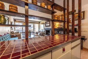 Eine Küche mit roter Fliesenrückwand, Holzbalken und Regalen mit Gläsern, die mit 'RICE' und 'BAIST' beschriftet sind.