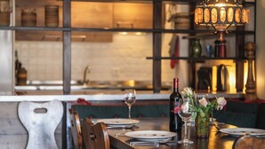 A restaurant interior with a wooden dining table set for two, a wine bottle, and a vase with flowers. - Luxury  in Perfect Location, Valais  1410 (Valais)
