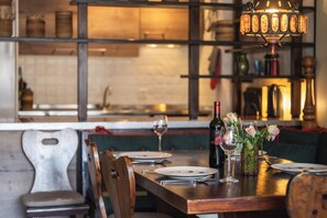 Ein Restaurantinterieur mit einem Holztisch für zwei Personen, einer Weinflasche und einer Blumenvase.
