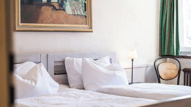 A hotel room with a bed, a lamp, a chair, and a painting on the wall. - Luxury  in Perfect Location, Valais  1410 (Valais)