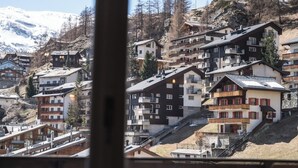 A mountain village with multi-story buildings, steeply sloped roofs, and a backdrop of snow-capped mountains. - Luxury  in Perfect Location, Valais  1410 (Valais)
