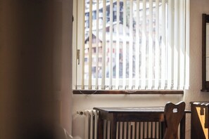 Een kamer met een raam, een radiator en een houten stoel.