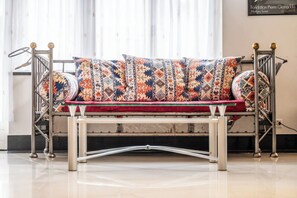 Ein modernes Metallsofa mit gemusterten Kissen in einem gut beleuchteten Raum mit Fliesenboden.