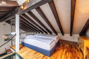A bedroom with a sloped ceiling, a bed, wooden flooring, and a dresser. - Alpine Serenity with Iconic Mountain Views 1090 (Wallis)