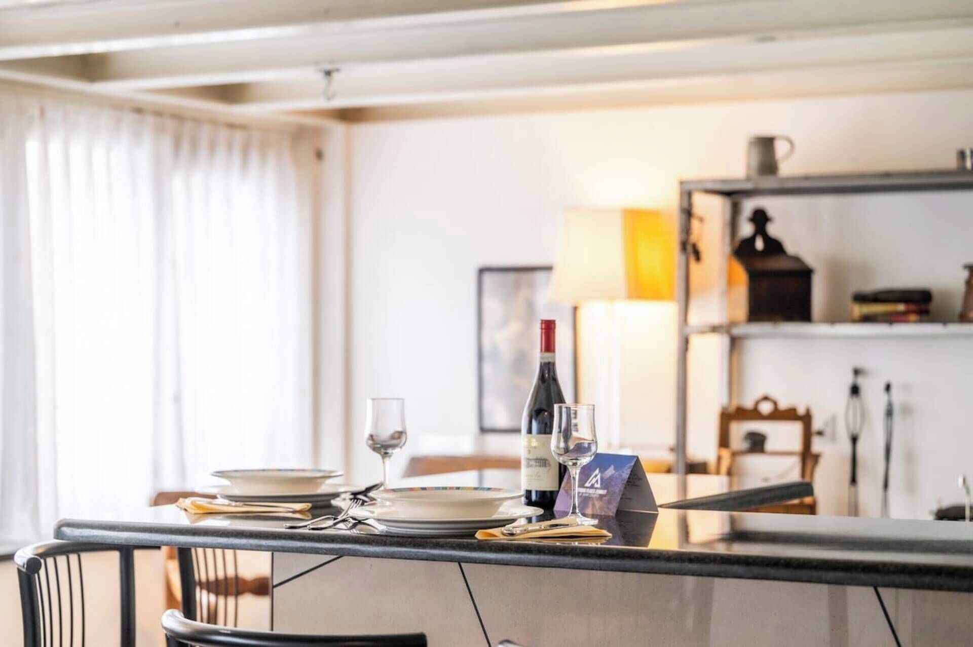 A dining area with a table set for two, a wine bottle, and a glass on the table.