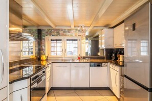Eine moderne Küche mit weißen Schränken, einer schwarzen Arbeitsplatte und einem Edelstahl-Kühlschrank.