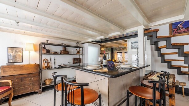A bar area with stools, a counter, and a view into the kitchen. - Alpine Serenity with Iconic Mountain Views 1090 (Wallis)