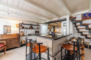 Zona de bar con taburetes, barra y vista a la cocina.