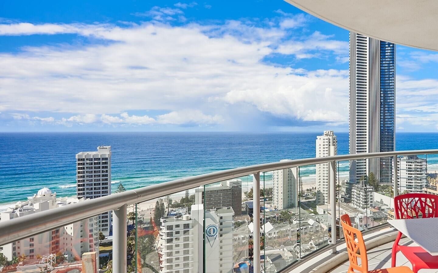 A balcony with a view of the ocean and cityscape, including high-rise buildings and a clear sky.
