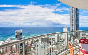 Ein Balkon mit Blick auf das Meer und die Stadtlandschaft, einschließlich Wolkenkratzern und einem klaren Himmel.