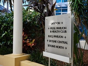 Een richtingsbord met pijlen die wijzen naar verschillende locaties, zoals Lagoon, Pool Pavilion & Health Club, B.B.Q. Pavilion, Skyline Central en Skyline North.