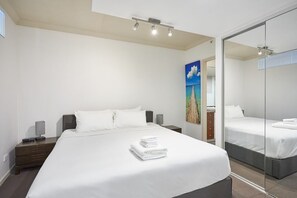 A modern hotel room with a large bed, a bedside table, a mirror, and a painting on the wall. - Ocean View 3BR Walk to Cavill Ave and the Beach (Surfers Paradise)