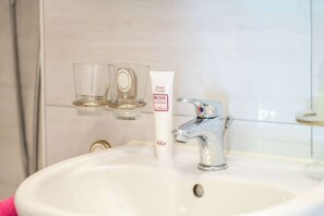 A bathroom sink with a hand cream tube labeled 'ROSE of Bulgaria' and two clear glasses on a shelf. - Your Elegant  Mountain Retreat 1103 (Ticino)