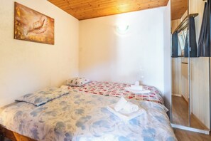 A bedroom with a bed, a painting, and a window. - Your Elegant  Mountain Retreat 1103 (Ticino)