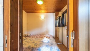 Quarto com cama, guarda-roupa e uma pequena cozinha.