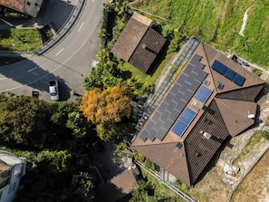 Ein Wohngebäude mit geneigtem Dach, Solaranlagen und einer gewundenen Auffahrt.