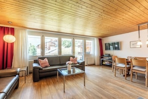 A modern living room with a sofa, coffee table, and dining area. - Effortless Alpine Living 1411 (Valais)