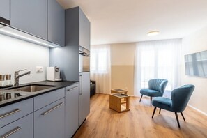 Une cuisine moderne avec des meubles gris, un évier en acier inoxydable et une table d’appoint en bois.