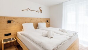 A double bed with white linens, a wooden headboard, two wall-mounted nightstands, and a decorative wall piece. - A Beautiful Alpine Escape in Zermatt 1092 (Wallis)