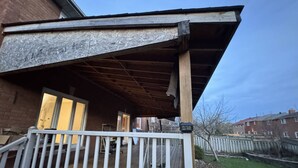 Ein Wohngebäude mit Holzterrasse, überdachter Veranda und Ziegelaußenwand.