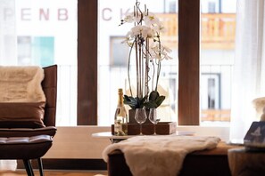 A modern interior with a sofa, a small table with a vase of flowers, and a bottle. - Contemporary Alpine Escape with Views 1409 (Valais)