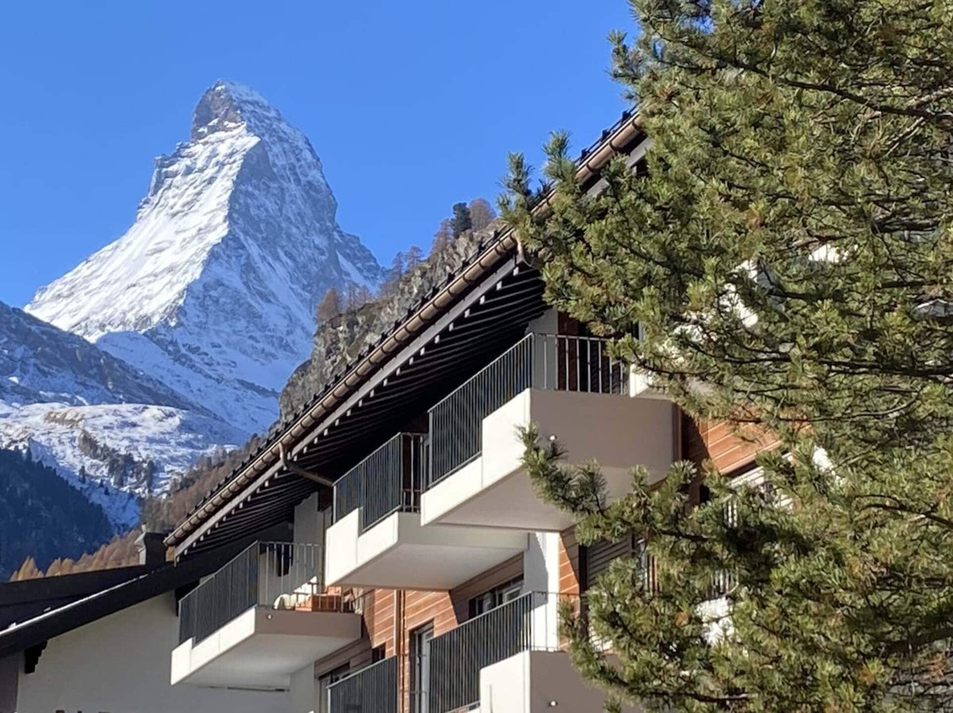 Een gebouw met balkons met uitzicht op een berg met sneeuw.