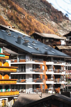 A multi-story hotel with balconies, a ski slope in the background, and a mountainous landscape. - Contemporary Alpine Escape with Views 1409 (Valais)