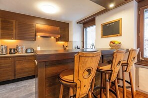 Eine moderne Küche mit Holzschränken, einer Bar und einem 'WELCOME'-Schild an der Wand.