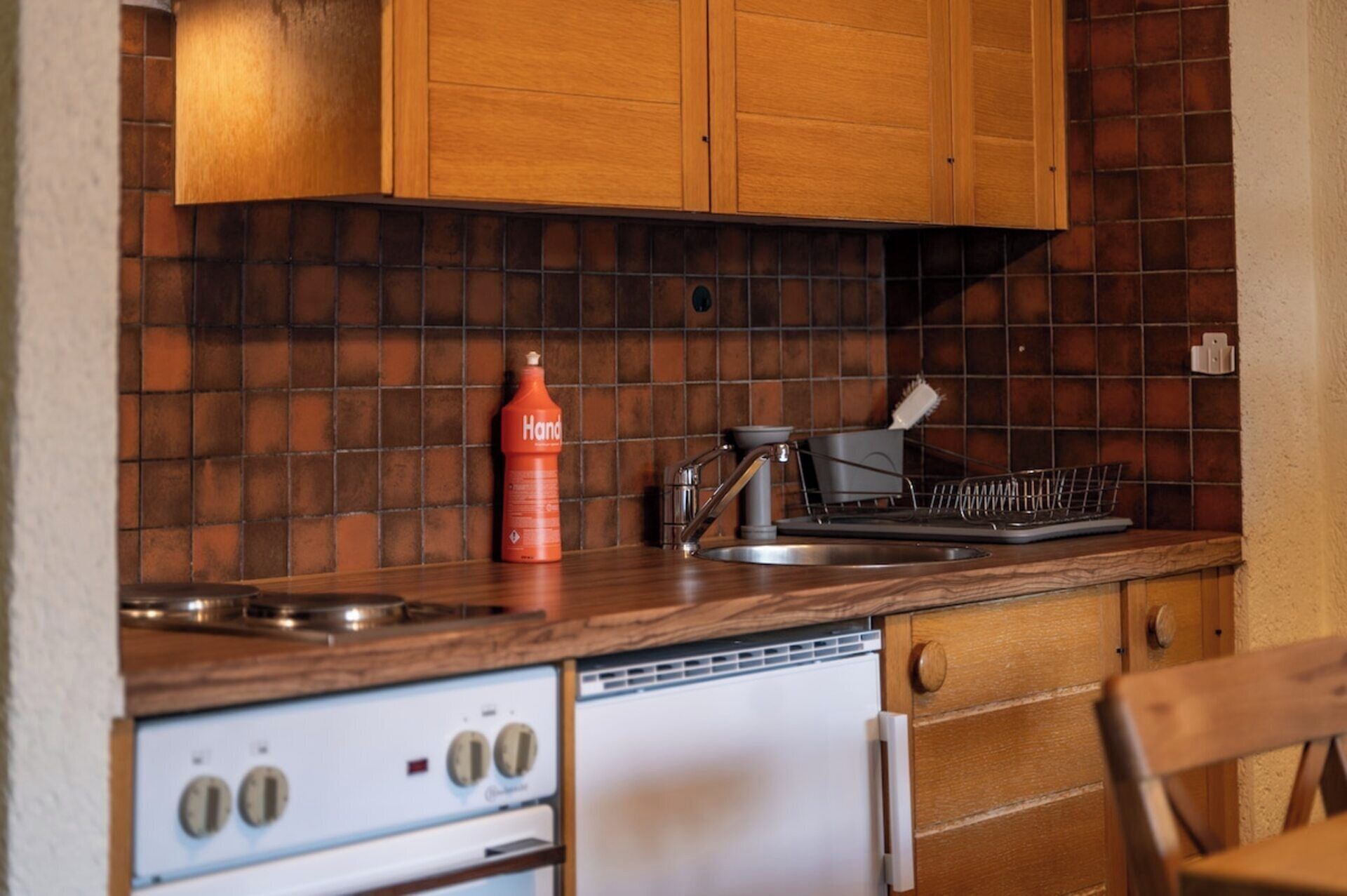 Una cocina con gabinetes de madera, una estufa y un escurreplatos.