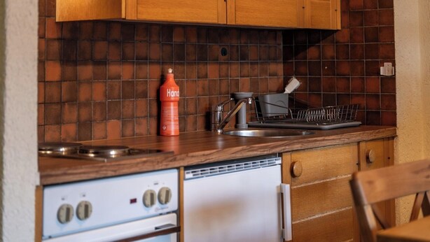 A kitchen with wooden cabinets, a stove, and a dish rack. - Serene Alpine Luxury in Zermatt 1089 (Wallis)
