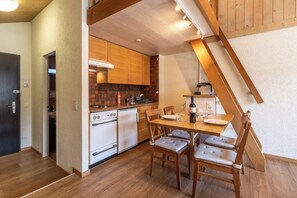 Eine kleine Küche mit Holzausstattung, einem Esstisch mit Stühlen und einer Treppe.