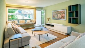 A modern living room with a sofa, a coffee table, a TV stand, and a painting on the wall. - Alpine Elegance with Matterhorn Views 1083 (Wallis)