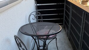 A balcony with a round metal table and two chairs, one with a floral cushion. - Alpine Elegance with Matterhorn Views 1083 (Wallis)