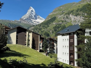 Ein modernes Hotel mit Blick auf die Berge, im Hintergrund ein markanter Berggipfel.