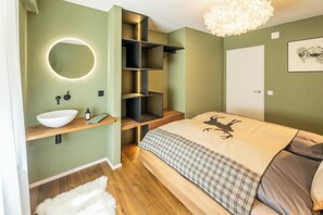 Une chambre à coucher comprenant un lit, une table de chevet, un miroir et une bibliothèque intégrée.