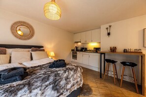 A bedroom with a bed, a bedside lamp, a round mirror, and a fur throw. - Wake to the Matterhorn in Luxury 1084 (Wallis)