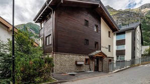 A two-story building with a stone foundation and a dark wooden facade. - Wake to the Matterhorn in Luxury 1084 (Wallis)